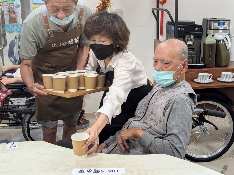 《圖說》板橋榮家陳桂美主任及行動咖啡志工傳遞溫暖咖啡給住民長輩伯伯。〈板橋榮家提供〉